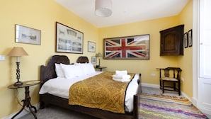 Een hotelkamer met een bed, een lamp, een ingelijst beeld, een vlag en een vloerkleed.