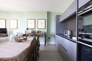 A modern kitchen with grey cabinets, a dining area with a patterned tablecloth, and framed botanical prints on the wall. - Spacious Apartment close to Edinburgh Castle (Edinburgh)