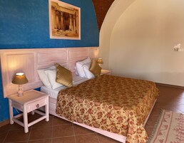 Un dormitorio con una cama, mesitas de noche, una lámpara y un cuadro en la pared.