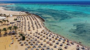 En la playa, sillas reclinables de playa, sombrillas, toallas de playa