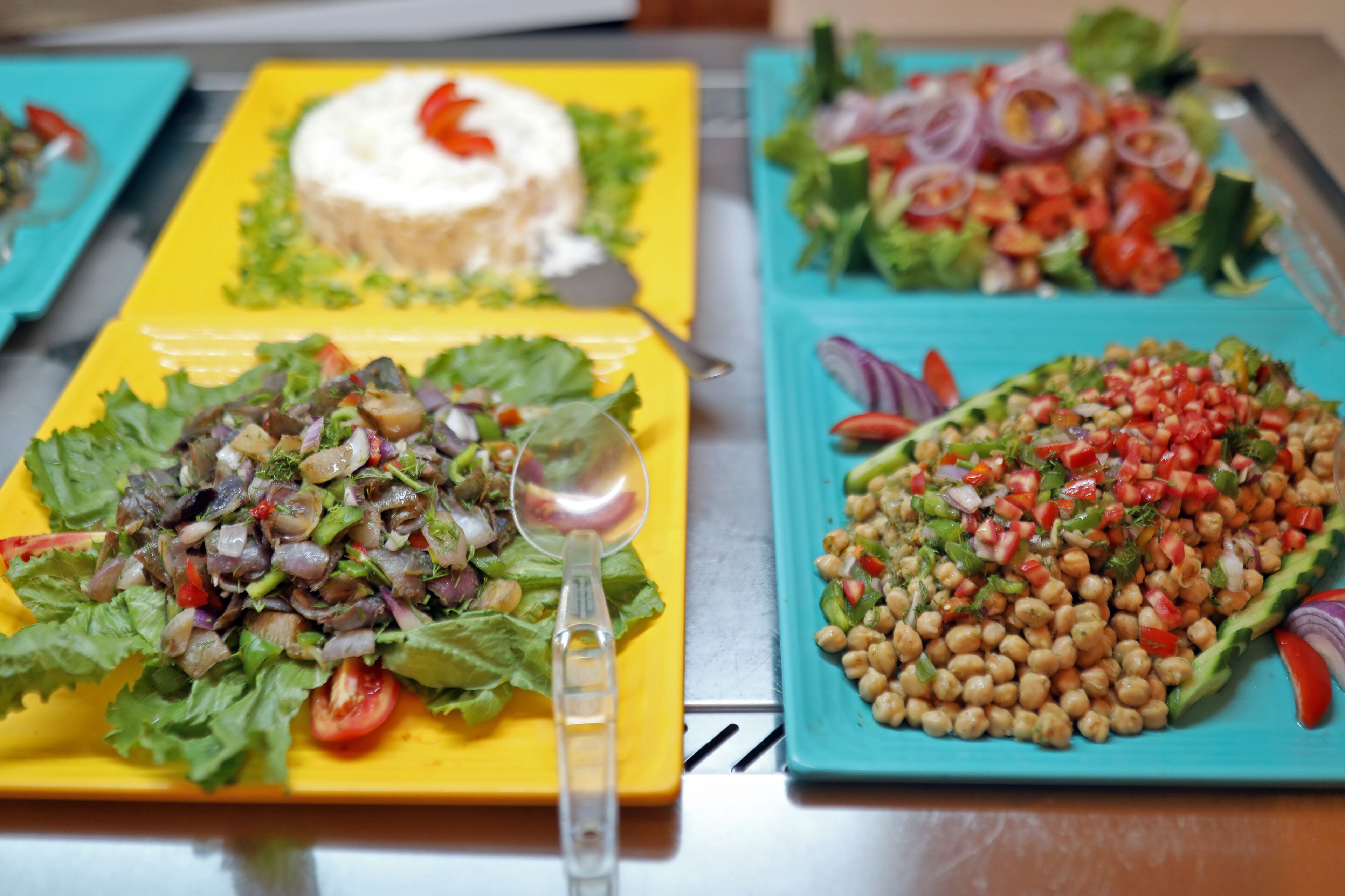 A table with three plates of food: a salad, a chickpea dish, and a salad with a dollop of cream.