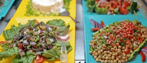 A table with three plates of food: a salad, a chickpea dish, and a salad with a dollop of cream.