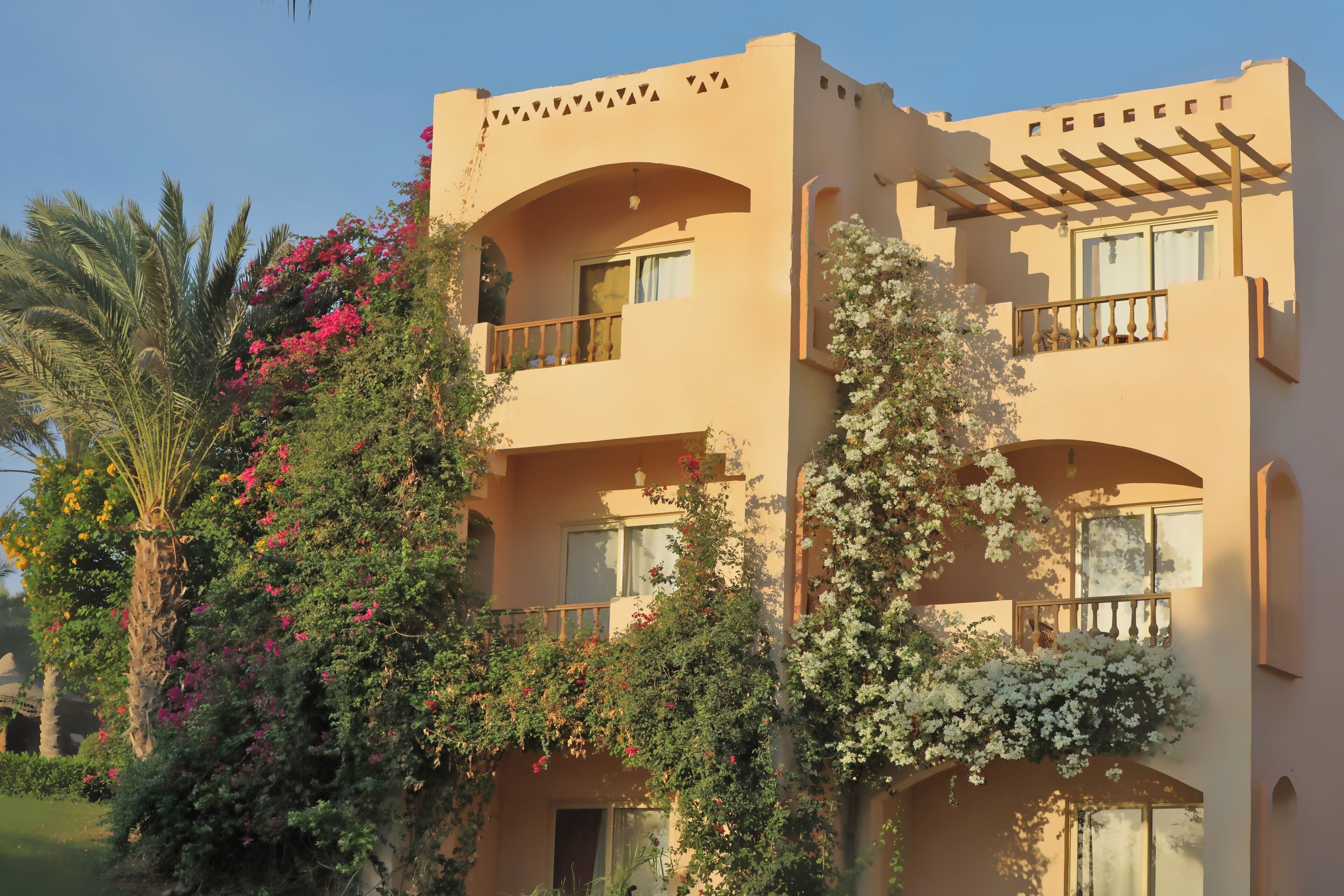 A multi-story building with balconies, arched windows, and a pergola.
