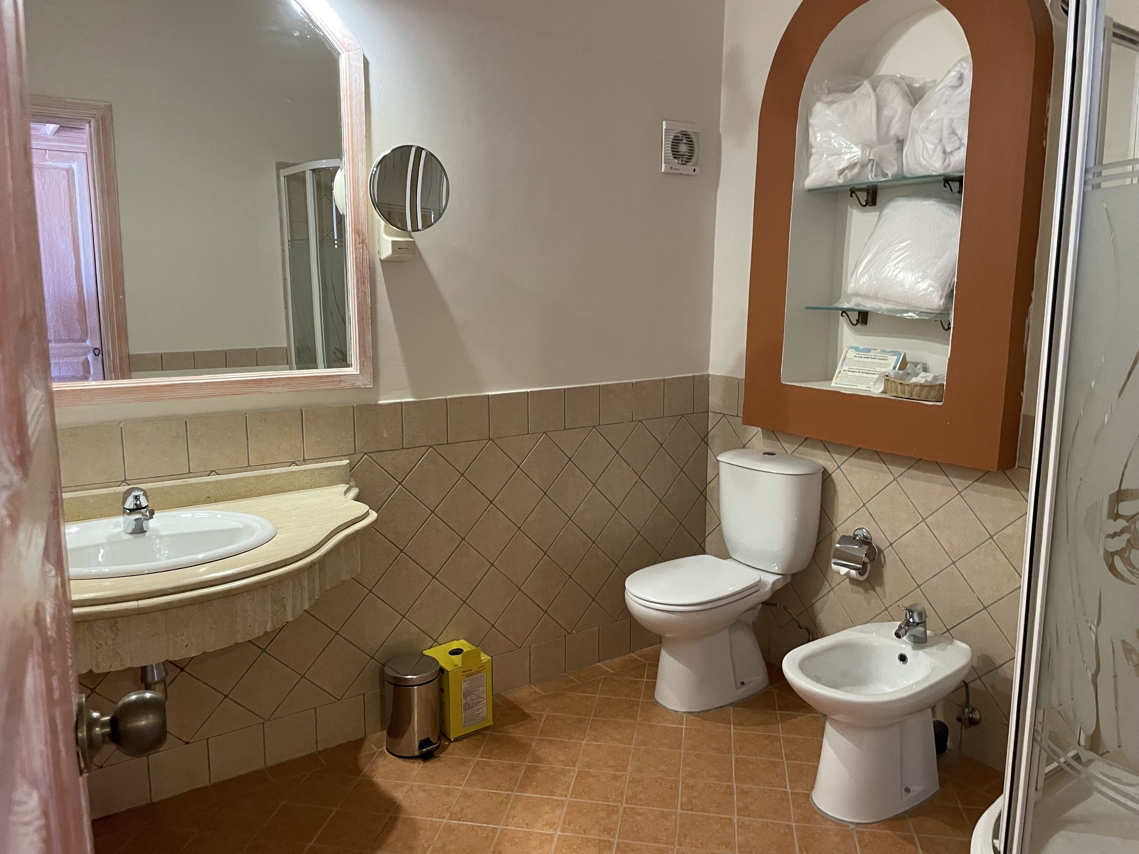 A bathroom with a sink, toilet, bidet, and a mirror.