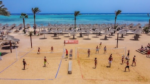 A beach volleyball court with a net, palm trees, and beach umbrellas. - TH Blue Lagoon Marsa Alam (Marsa Alam)