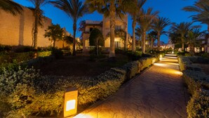 A well-lit pathway with palm trees and a building in the background. - TH Blue Lagoon Marsa Alam (Marsa Alam)