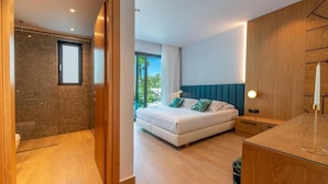 A modern bedroom with a bed, wooden headboard, bedside table, and a view of the outdoors. - Glamorous Villa with Two Swimming Pools and great view (Chania)