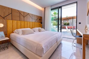 A modern hotel room with a large bed, a desk, and a view of the outdoor patio.