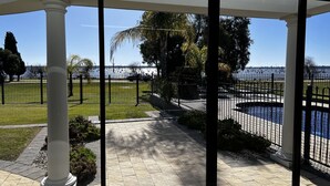 A covered outdoor area with a view of a body of water, a paved walkway, and a fenced garden. - Luxury resort style living on Lake Mulwala with breathtaking views & pool/sauna! (Yarrawonga)