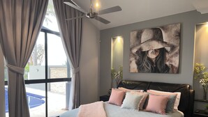 A modern bedroom with a large bed, a ceiling fan, and a view of a swimming pool. - Luxury resort style living on Lake Mulwala with breathtaking views & pool/sauna! (Yarrawonga)