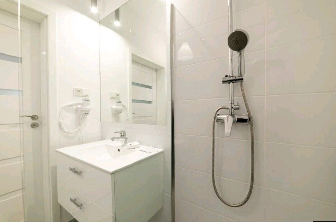 A modern bathroom with a white vanity, a mirror, and a shower with a handheld showerhead.