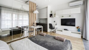 Une chambre d’hôtel moderne équipée d’un grand lit, d’un bureau, d’une chaise, d’une télévision et d’une kitchenette.