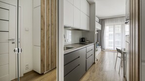 Une cuisine moderne avec des meubles blancs, un mur d’accent en bois et un coin repas comprenant une table et des chaises.