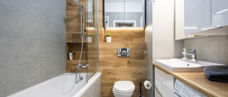 Un baño moderno con bañera, inodoro y lavadora.