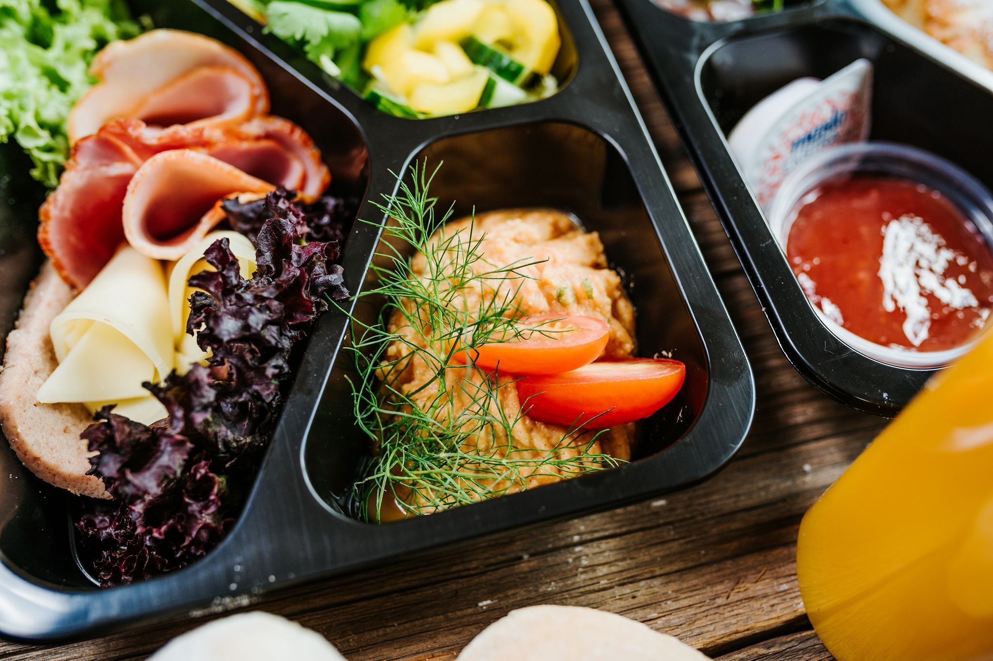 A meal tray with various food items including meats, cheese, and vegetables.