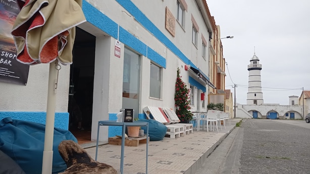 Ein Gebäude mit blau-weißer Fassade, einem Schild und einer kleinen Weihnachtstanne.