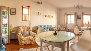 Ein Wohnzimmer mit Glastisch, gemusterten Sofas, einem Fernseher und einem Kühlschrank.