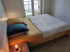 Cozy retreat with a single bed, bedside table, and glass lamp, offering a peaceful view of the surrounding greenery.