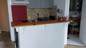 Eine kompakte Küche mit grauen Schränken, einer Holz Arbeitsplatte und einer weißen Kücheninsel.