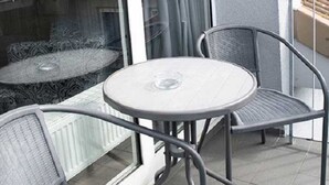 A balcony with a glass door, two chairs, and a small round table. - Schiller- Quartier 6 apartment "Heimathafen" (Bremerhaven)