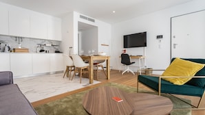 A modern living room with a sofa, a coffee table, and a TV mounted on the wall.