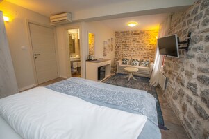 Un dormitorio con cama, escritorio, televisor y pared de piedra.