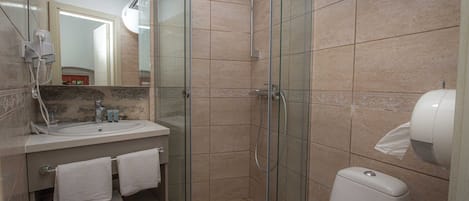 A modern bathroom with a glass-enclosed shower, a sink with a mirror, and a toilet.