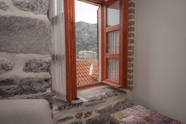 Una habitación con paredes de piedra y una puerta de madera que da a un balcón con vistas a una zona montañosa.