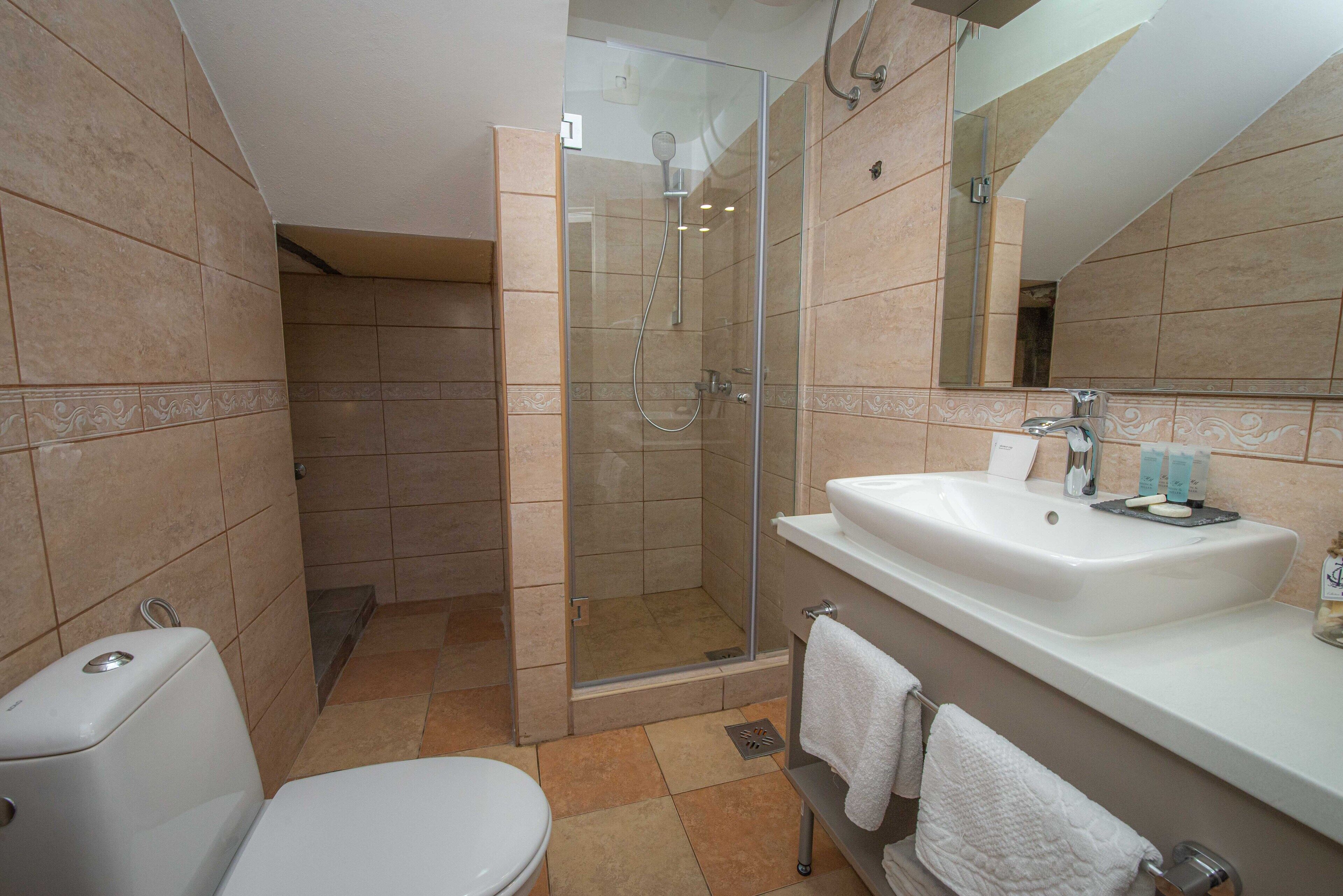 Un baño con ducha envuelta en cristal, un lavabo blanco y un inodoro.