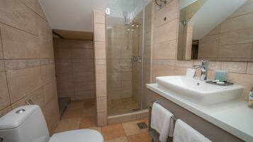 Un baño con ducha envuelta en cristal, un lavabo blanco y un inodoro.