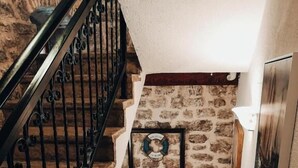 A stone staircase with a metal railing, a welcome sign, and a framed picture on the wall.