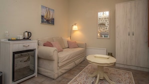 A cozy living room with a sofa, a small table, a cabinet, and a painting on the wall.