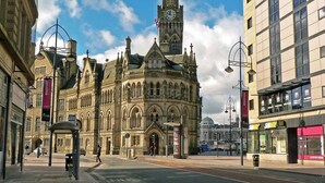 A historic building with a clock tower, surrounded by modern buildings and a Subway restaurant. - Captivating 2-bed Apartment in Bradford (Bradford)