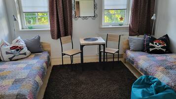 Ein gemütliches Zimmer mit zwei Betten, einem kleinen Tisch und Stühlen.