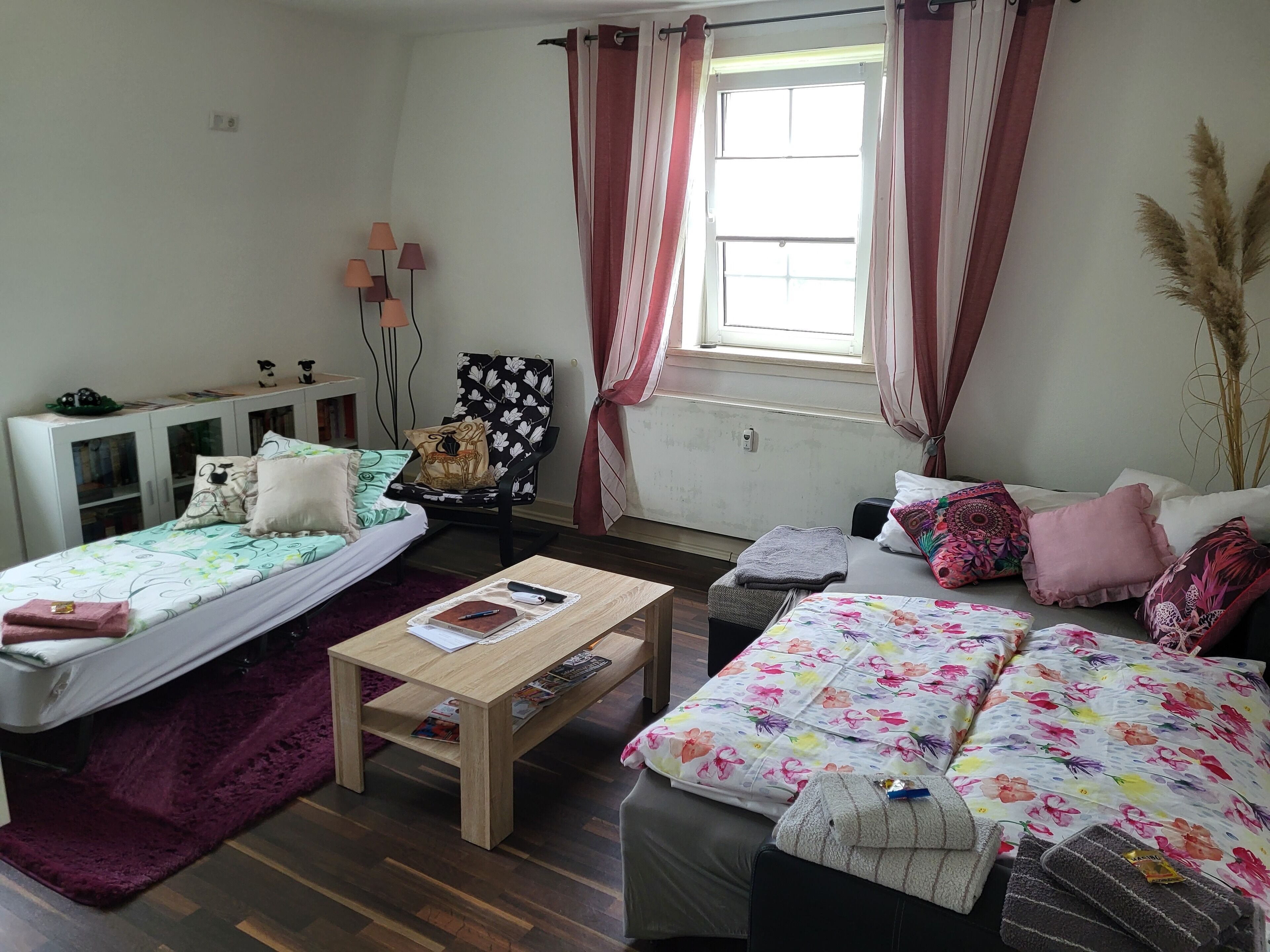 A well-lit room with two beds, a sofa, a small table, and a cabinet.