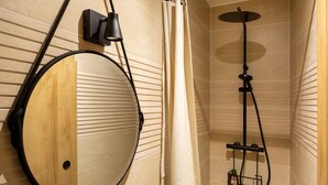 Ein Badezimmer mit einem Holzkosmetikschrank, einer Dusche mit Handbrause und einem Handtuchhalter.