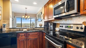Une cuisine moderne avec des meubles en bois, des appareils électroménagers en acier inoxydable et une grande fenêtre offrant une vue dégagée.