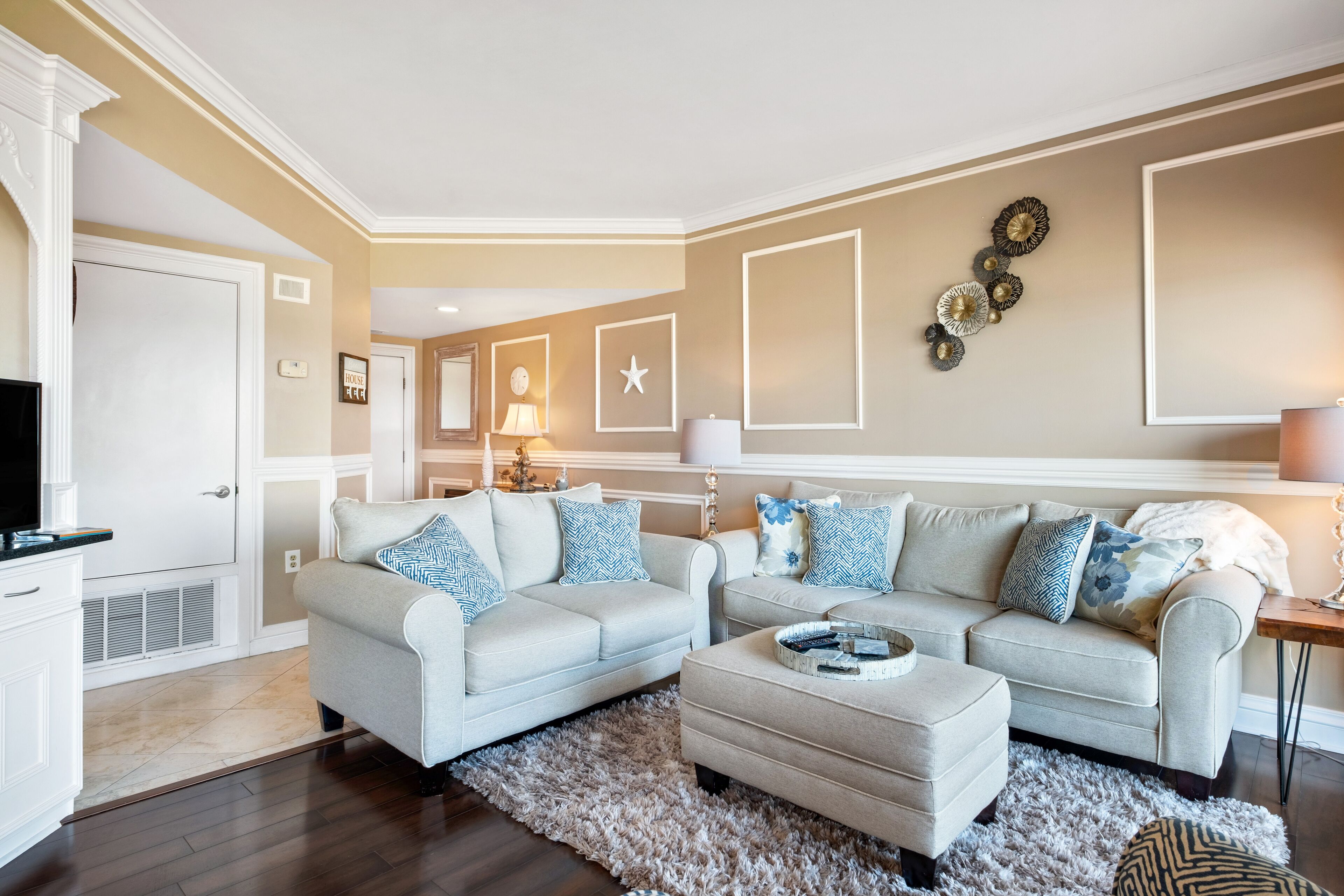 Un salon avec deux canapés, une table basse et un téléviseur. On y trouve également des éléments décoratifs sur les murs et une lampe.