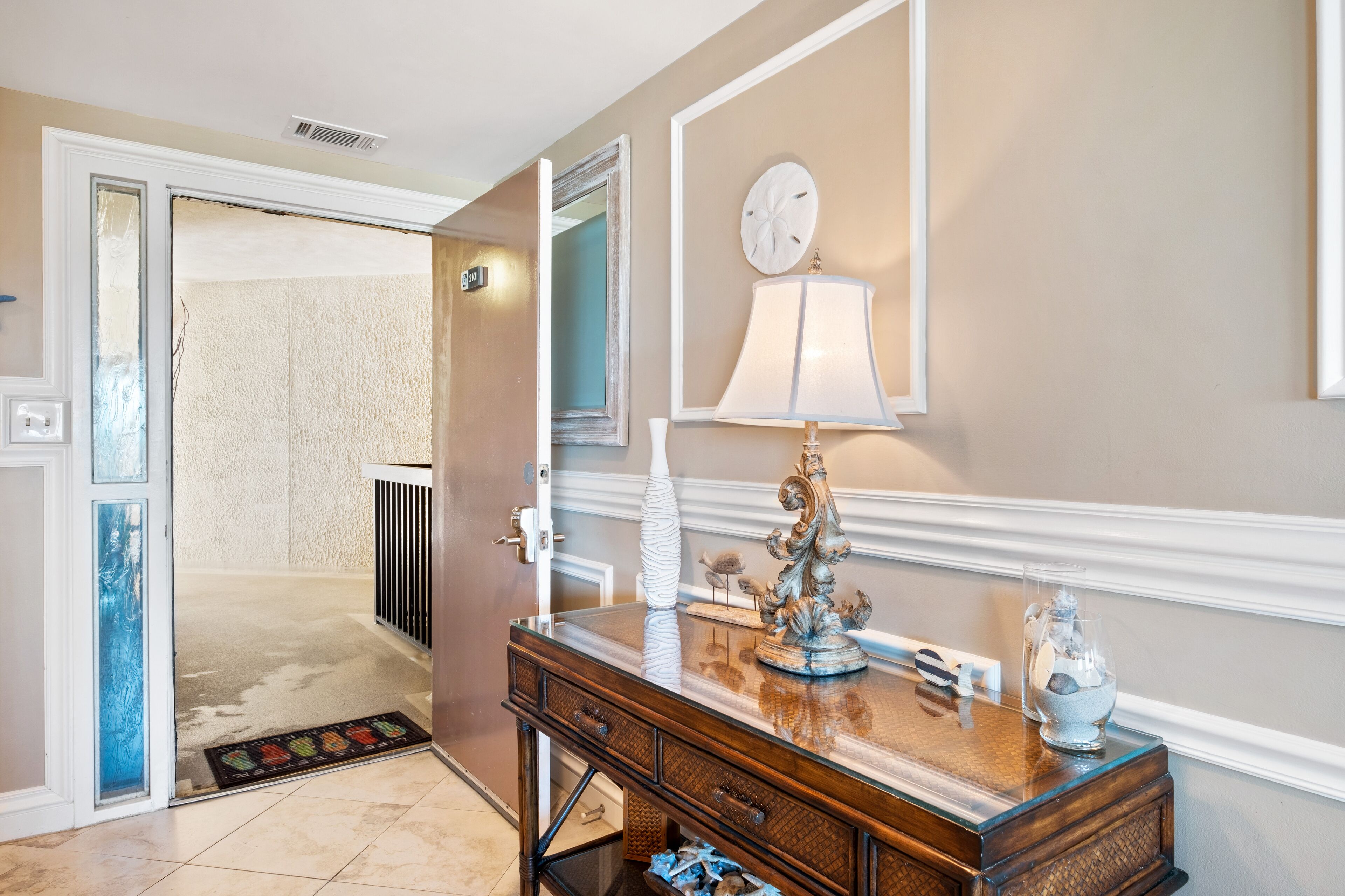 A hallway with a wooden console table, a lamp, and a decorative vase.