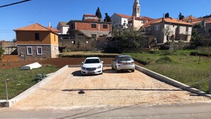 A parking area with two cars, surrounded by residential buildings and a church tower.