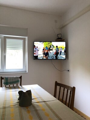 A dining area with a table, chairs, and a television mounted on the wall.