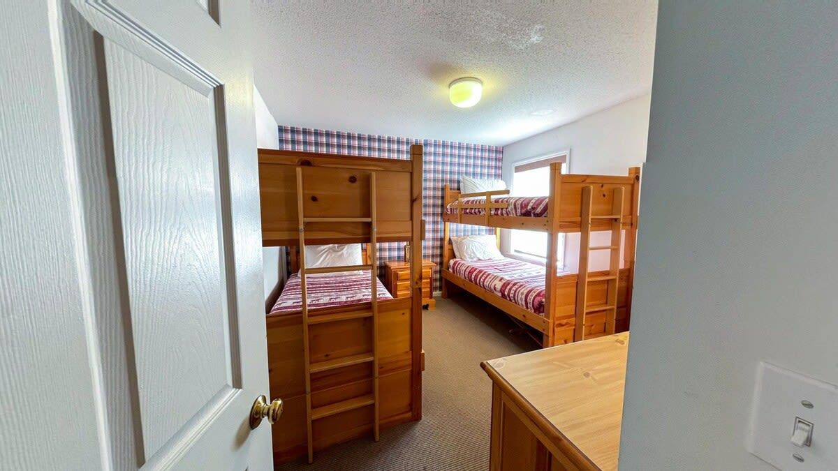 A room with bunk beds, a wooden desk, and a door.