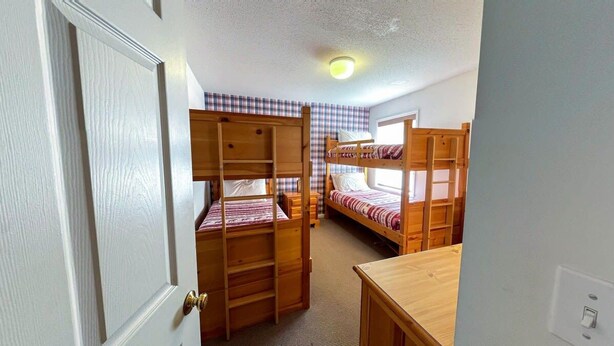 A room with bunk beds, a wooden desk, and a door. - Cozy 2 BR Ski-in/Ski-out Condo at Okemo (Ludlow)