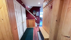 A hallway with wooden doors, a bench, and a staircase leading to another level. - Cozy 2 BR Ski-in/Ski-out Condo at Okemo (Ludlow)