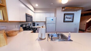Una cocina moderna con armarios blancos, un lavamanos de acero inoxidable y una estufa a gas.