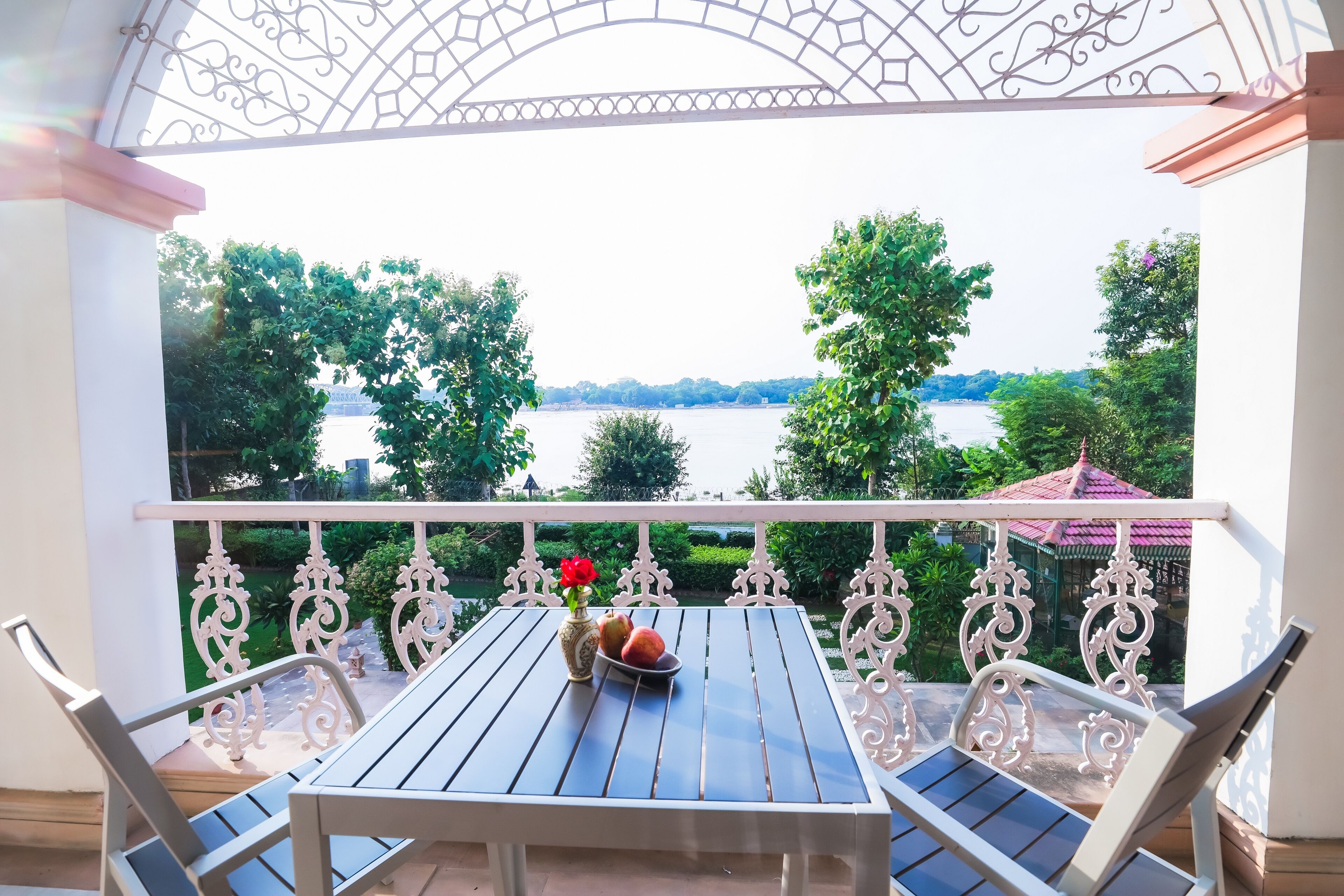 A balcony with a table, chairs, and a view of a body of water.