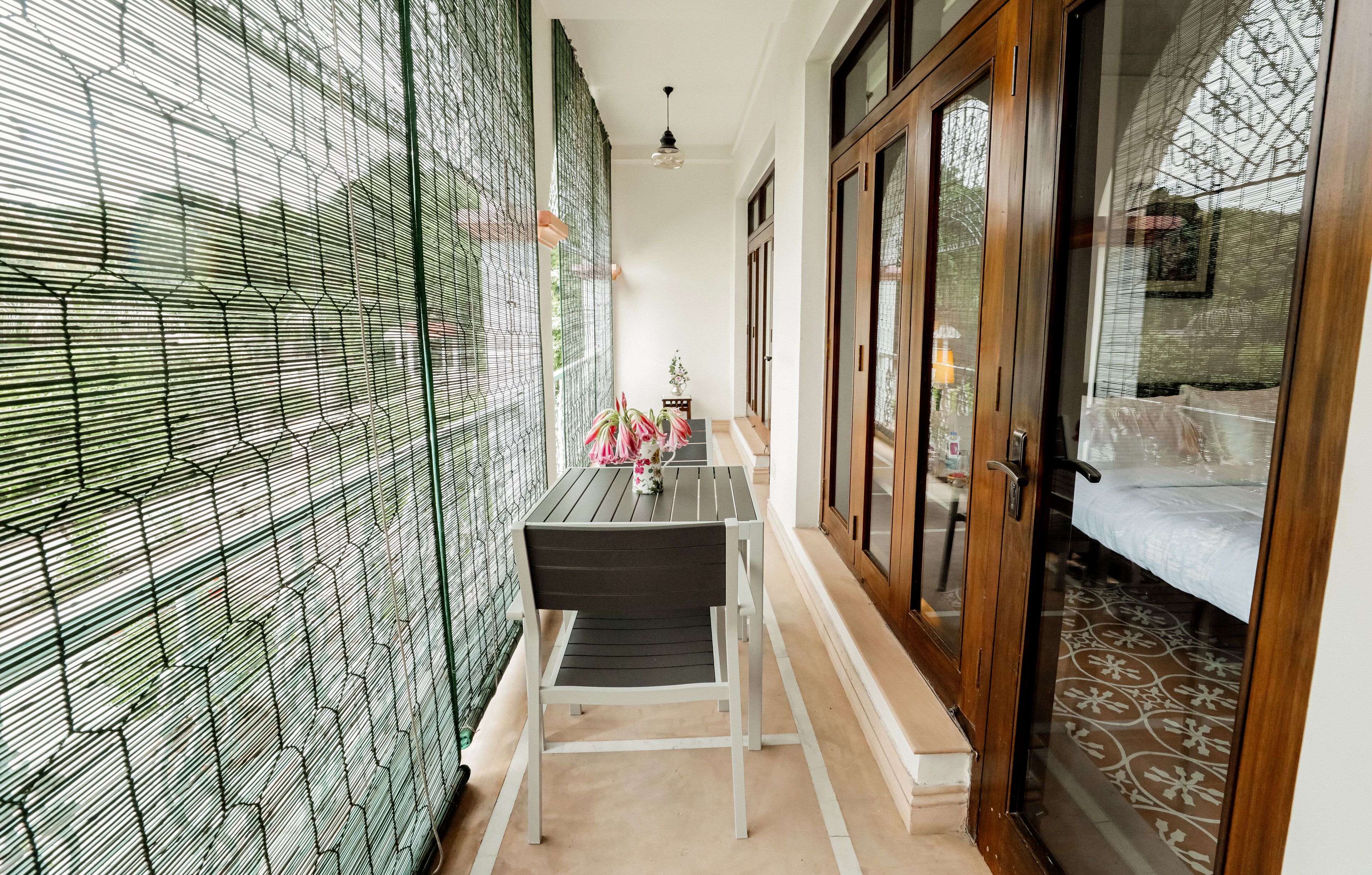 A narrow corridor with a table and chairs, a wooden door, and a patterned floor.