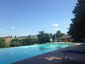 Une piscine offrant une vue sur la campagne environnante, avec des arbres et des bâtiments situés au loin.