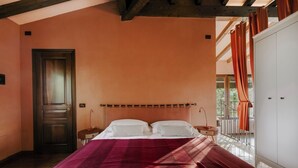A bedroom with a bed, nightstands, a wardrobe, and a view of the outdoors.