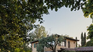 A house with a garden, a tree, and a small building.